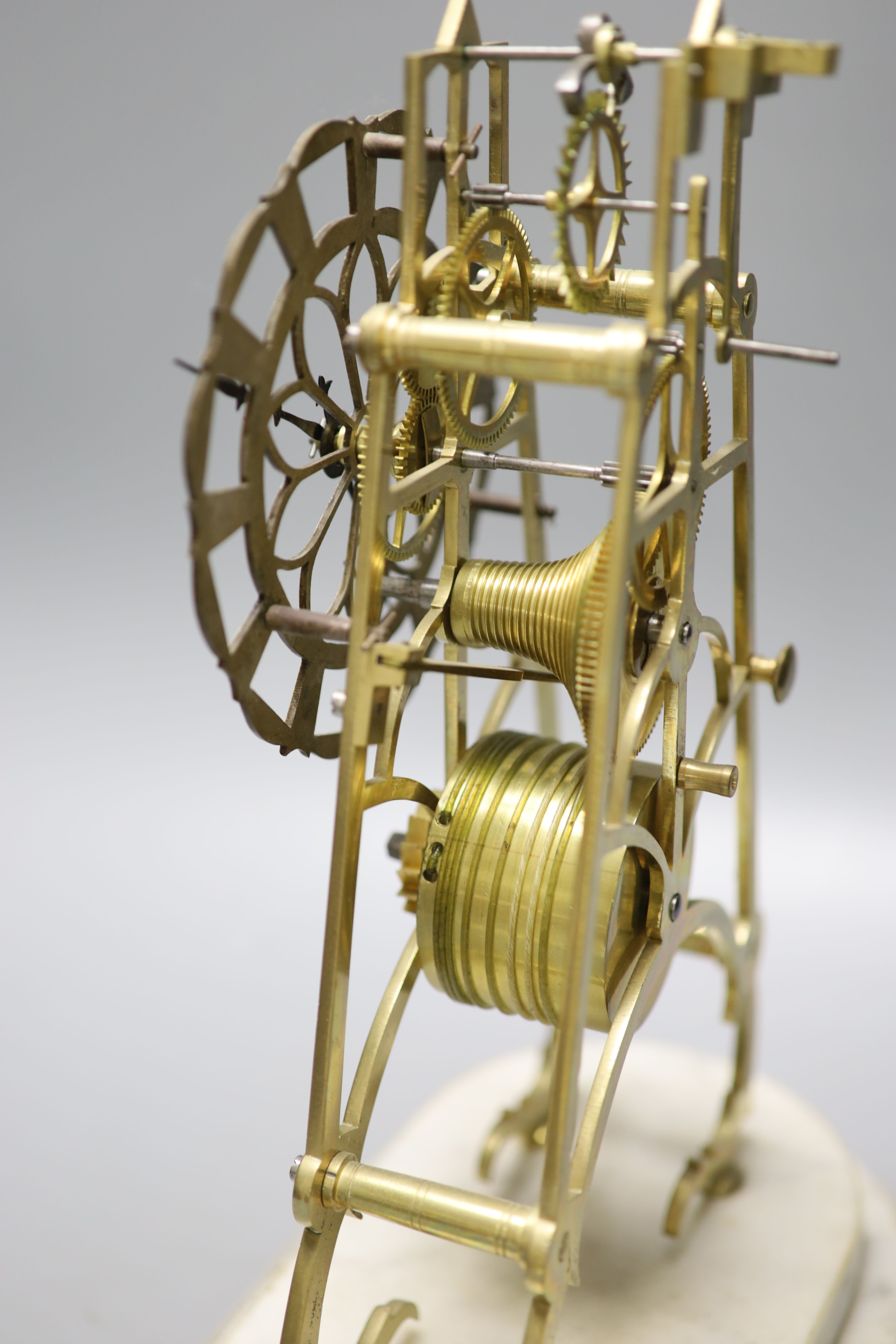 A 19th century brass skeleton clock on marble base. Associated glass dome, total height 44.5 cm